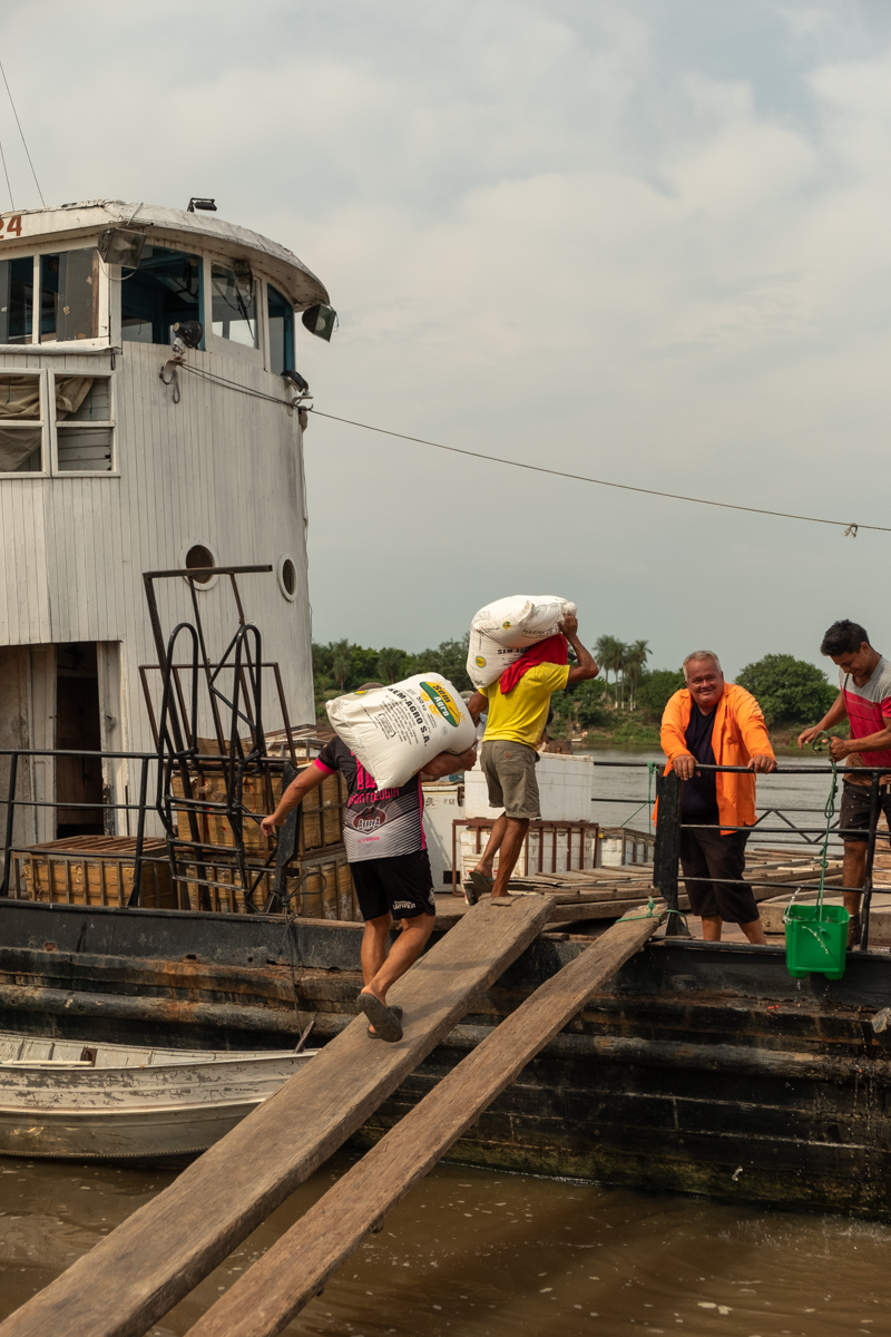 Passenger loading water bottles and supplies onto the deck of the Aquidaban at sunset, Río Paraguay