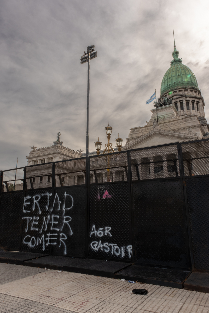 Worker dragging a sack of collected materials past stacked bales of compressed cardboard