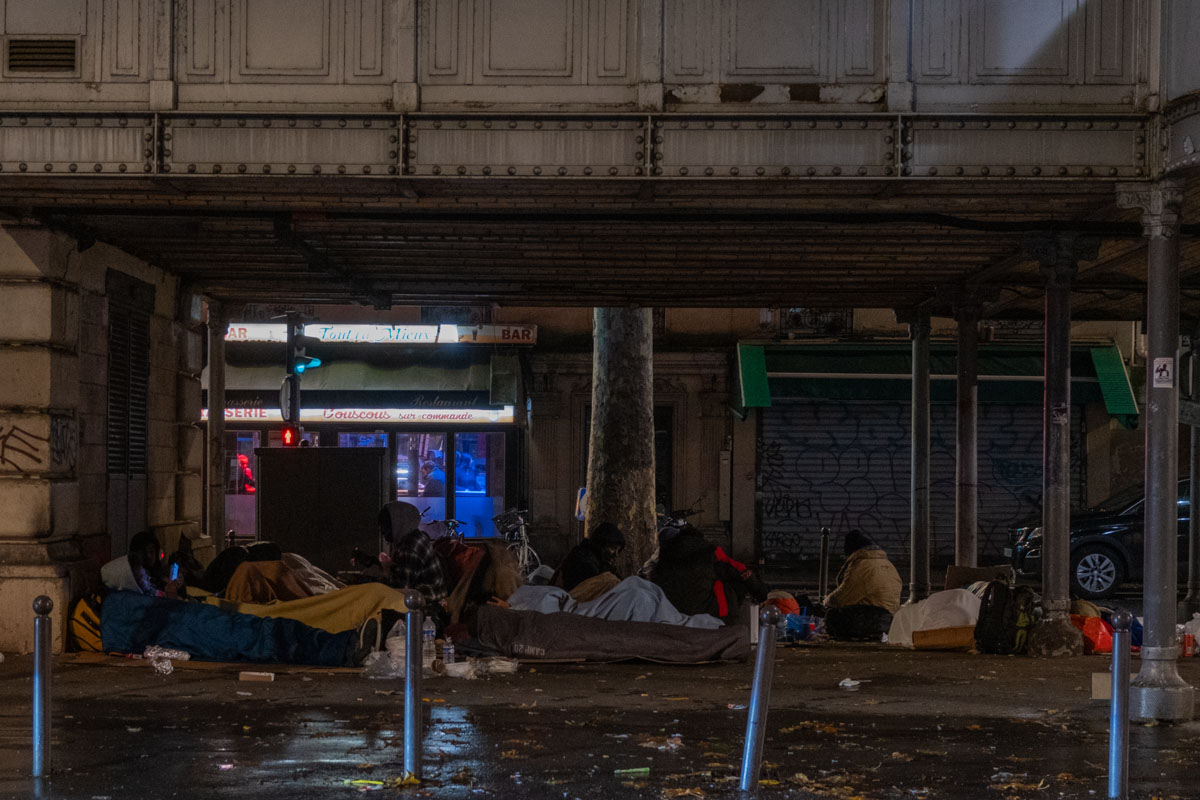 Abandoned mattress and sleeping bag on the concrete floor under a Paris motorway overpass at night