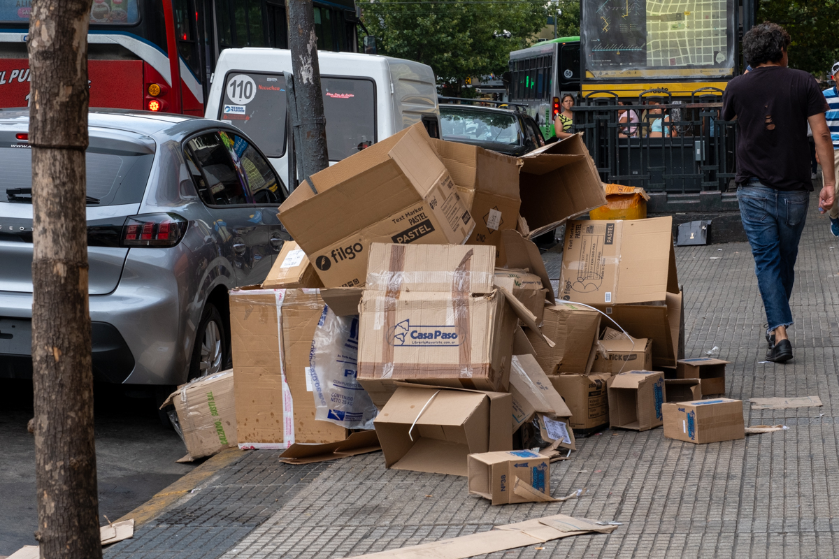 Young cartonero struggling to balance a heavily loaded carro on a Buenos Aires street