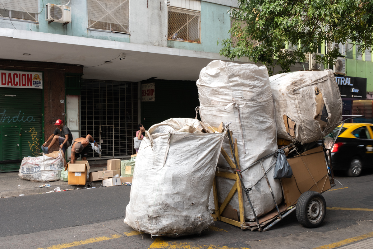 Cartonero posing with his trolley loaded with recovered goods beside a graffiti wall, Buenos Aires