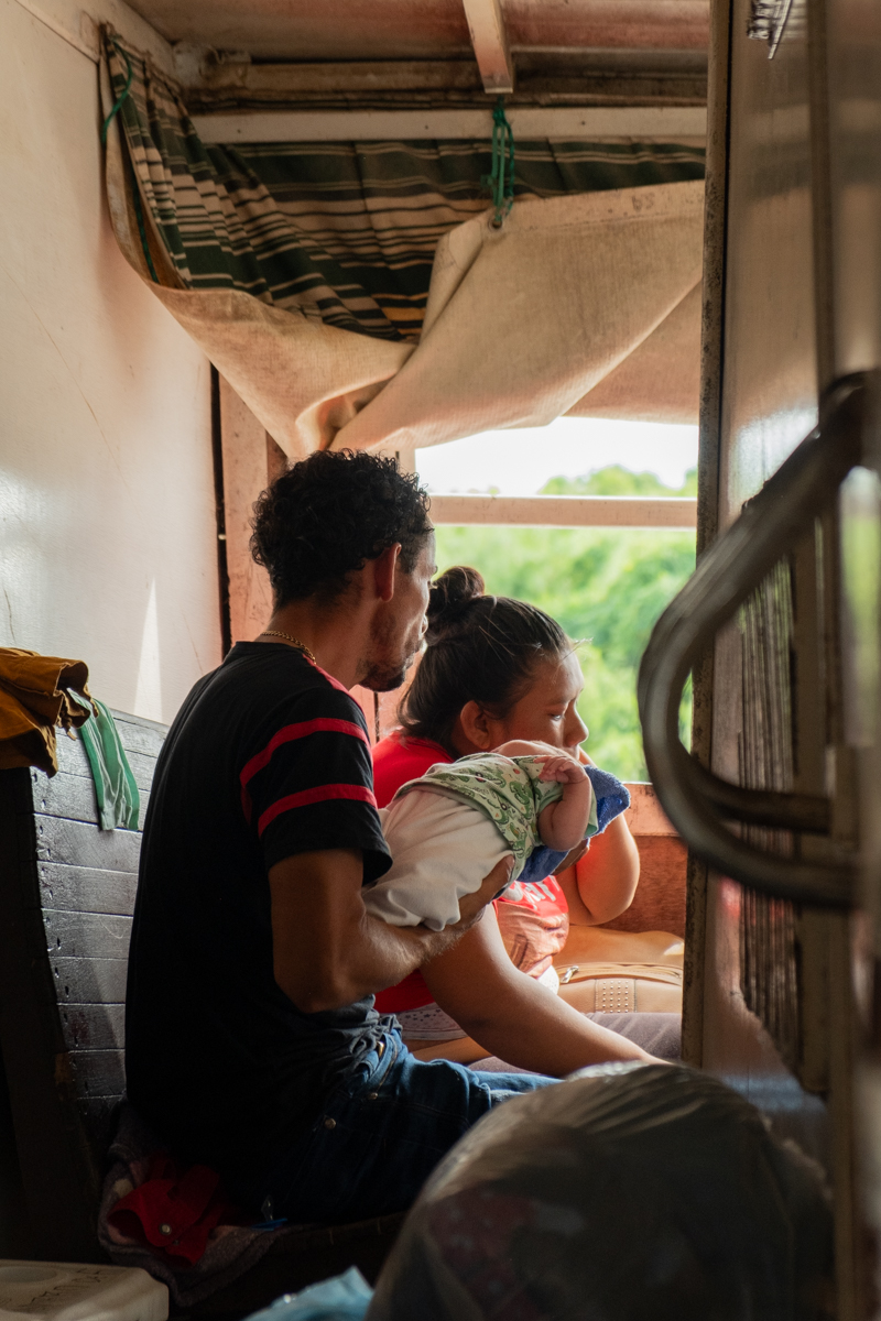 Elderly man repairing an electronic device between hammocks on the Aquidaban passenger deck