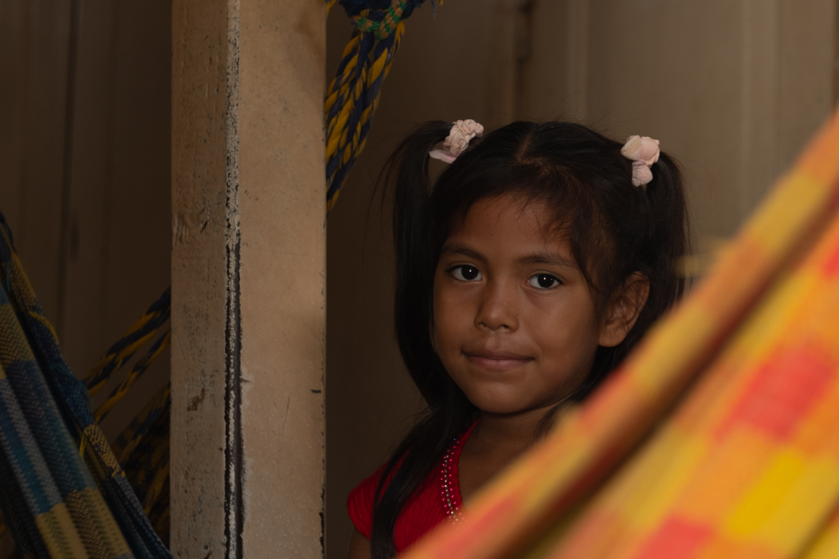 Passenger sleeping beside a crate of bananas and hanging goods in the hold of the Aquidaban