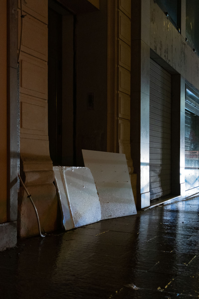 Homeless person sleeping on a mattress covered with a pink blanket under a colourful Paris mural at night