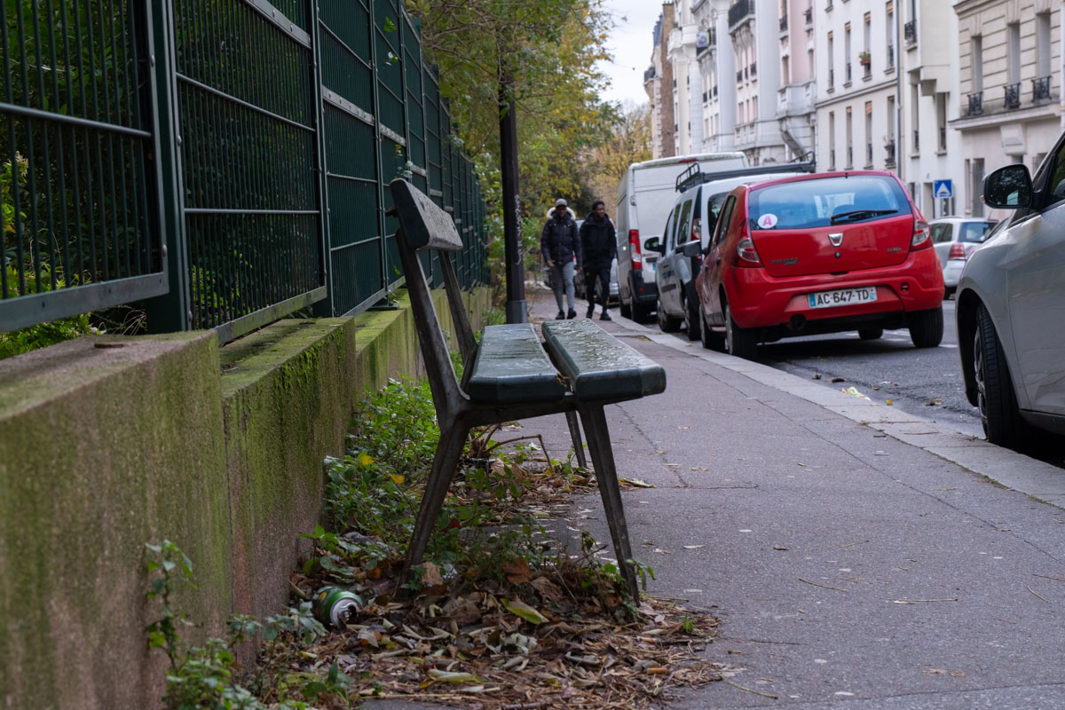 Empty Paris side street at night with bollards and red graffiti on a building wall