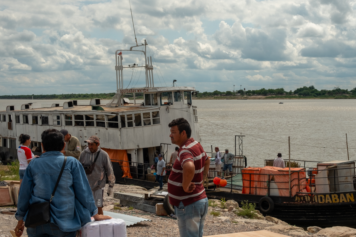 Hanging bags of bread rolls and stacked crates of fruit and vegetables in the cargo hold of the Aquidaban