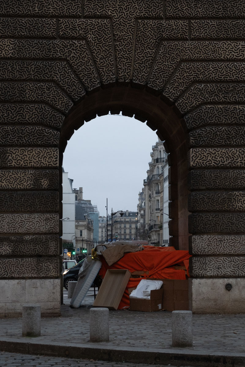 Row of large boulders placed under a Paris bridge to prevent rough sleeping, behind a metal fence