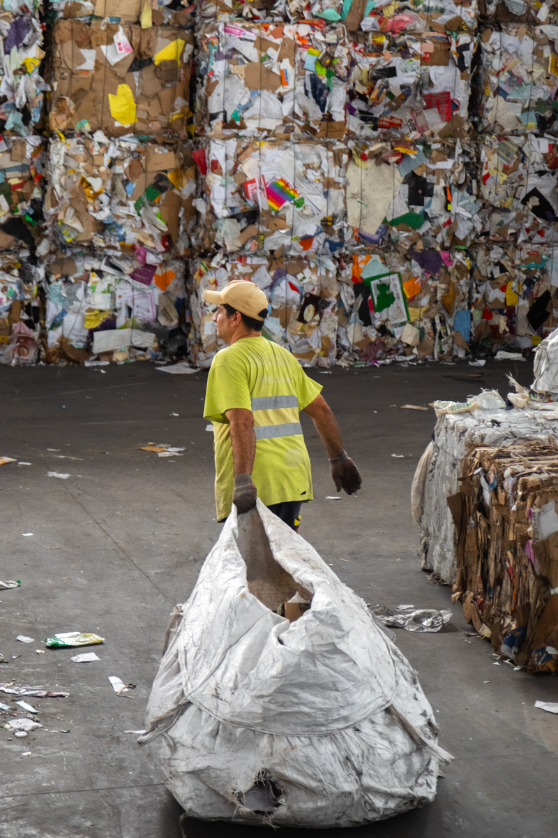 Argentine flag hanging beside industrial baling machinery inside a cartonero cooperative