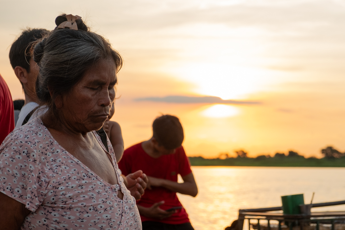 Young crew member breaking ice with a wooden mallet in a chest freezer on the deck of the Aquidaban