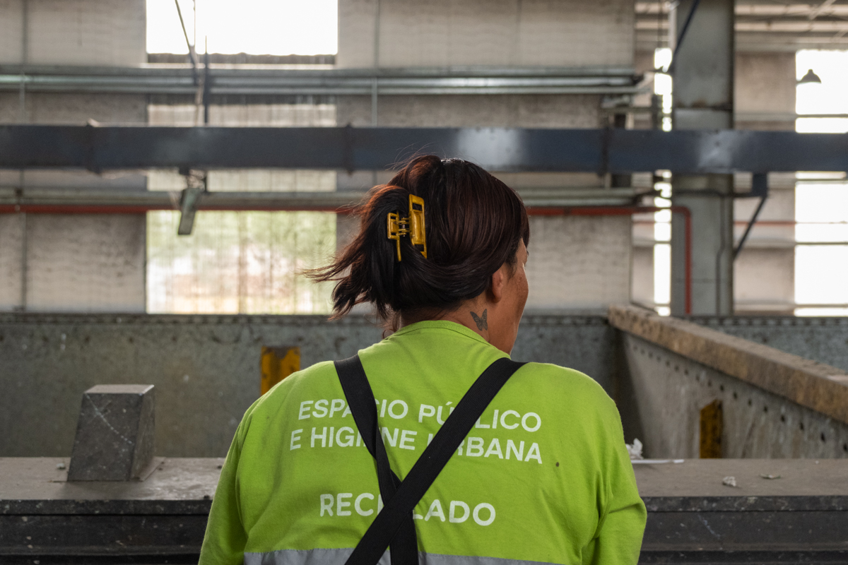Smiling cartonero in a yellow vest pushing his carro across a busy Buenos Aires intersection