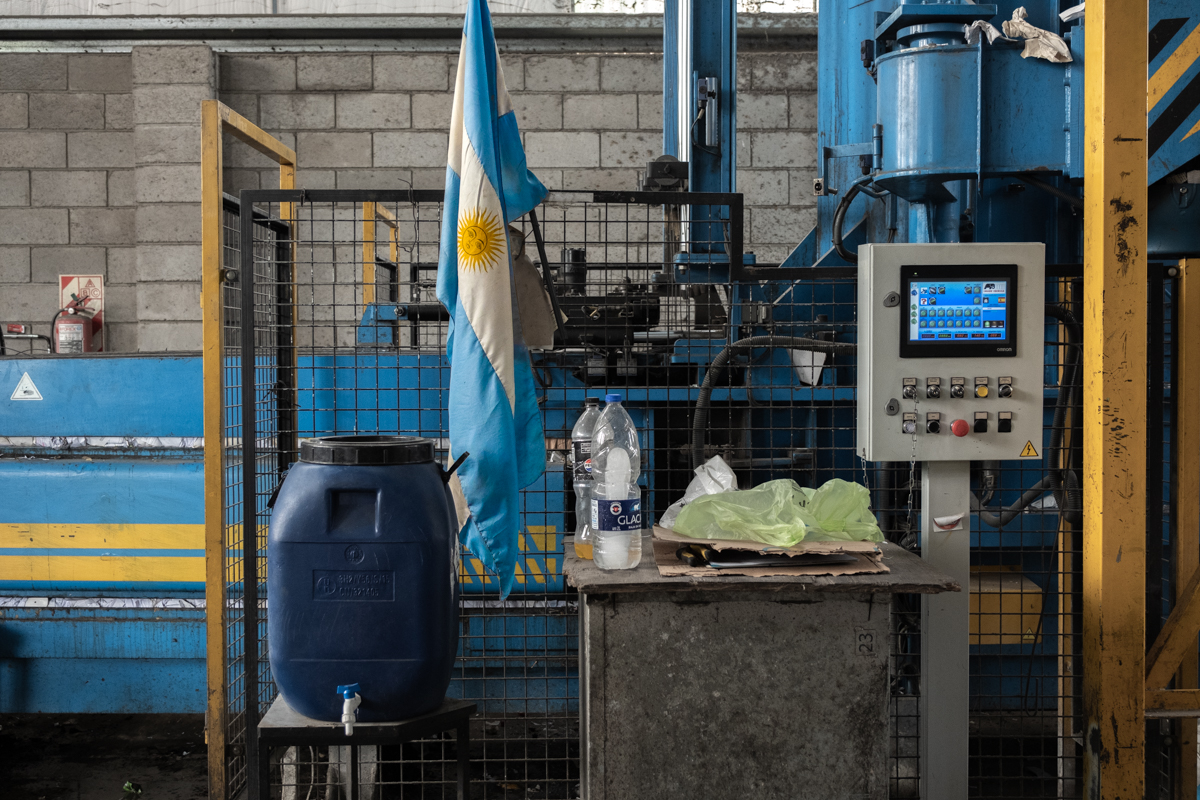 Group of cartoneros resting on a median strip beside a dumpster and shopping trolley, Buenos Aires